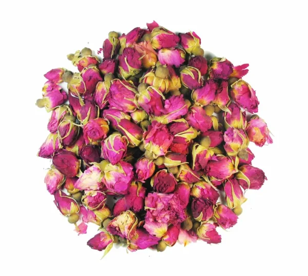 A cluster of dried pink Rosebuds forms a dense pile against a white background, showcasing the vibrant pink hues of the petals interspersed with touches of green from the stems and sepals.