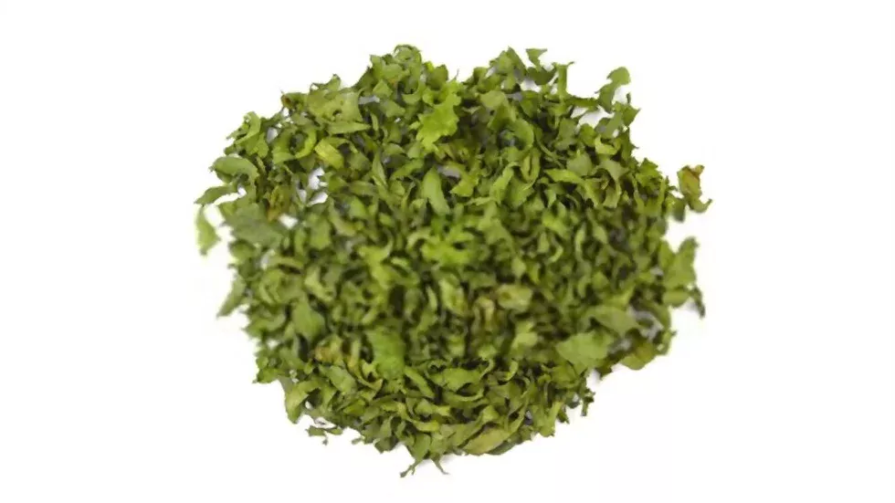 A pile of finely chopped dried celery leaves from the "Celery" product is scattered against a plain white background. The Egyptian leaves appear vibrant green, perfect for the food industry.