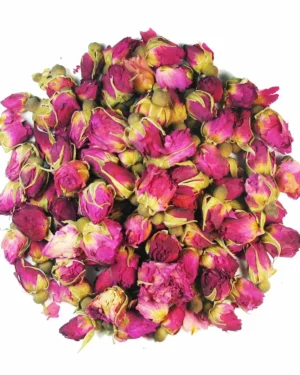 A cluster of dried pink Rosebuds forms a dense pile against a white background, showcasing the vibrant pink hues of the petals interspersed with touches of green from the stems and sepals.